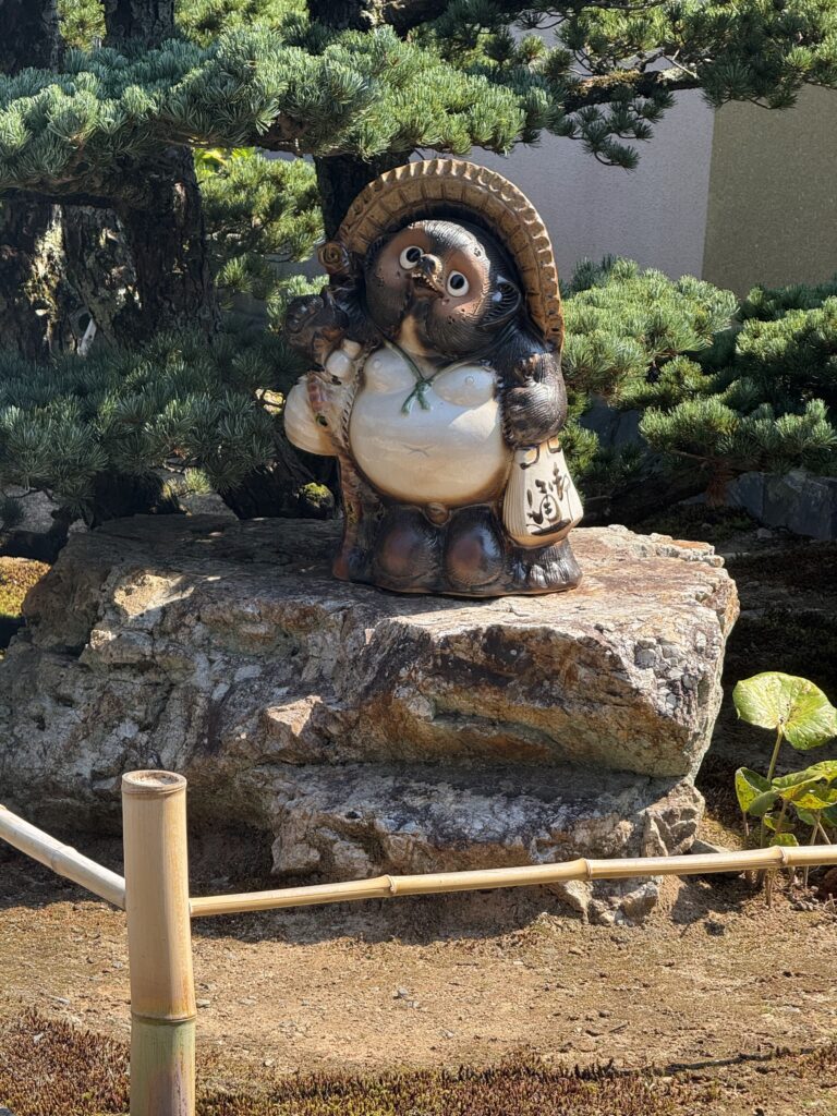 Traditional tanuki figure in Japanese temple garden Tanuki statue in Japanese garden symbolizing prosperity and good luck