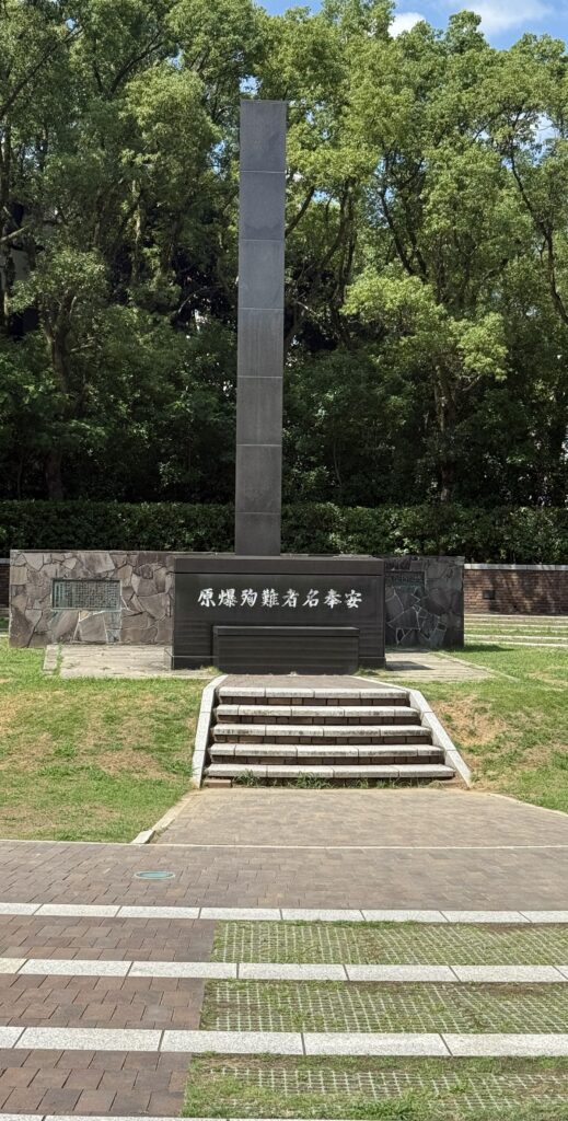 Hypocenter Cenotaph at Nagasaki Peace Park marking the atomic bomb ground zero with memorial inscriptions and surrounding greenery.