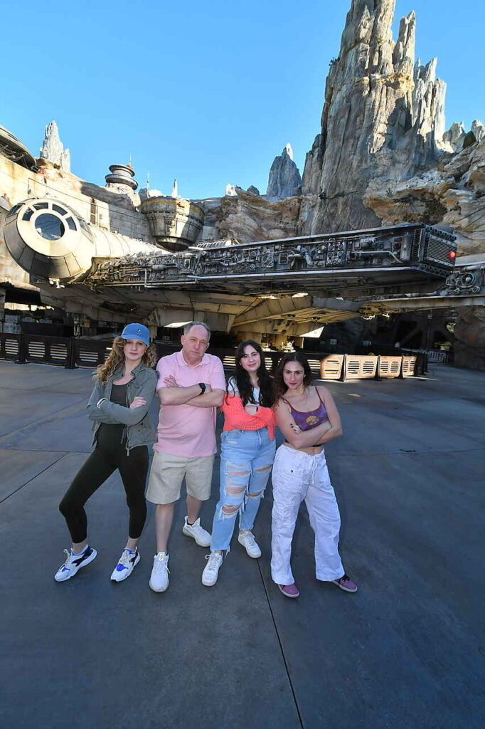 Multigenerational group of Disney Star Wars fans posing in front of the full-scale Millennium Falcon at Star Wars: Galaxy's Edge.