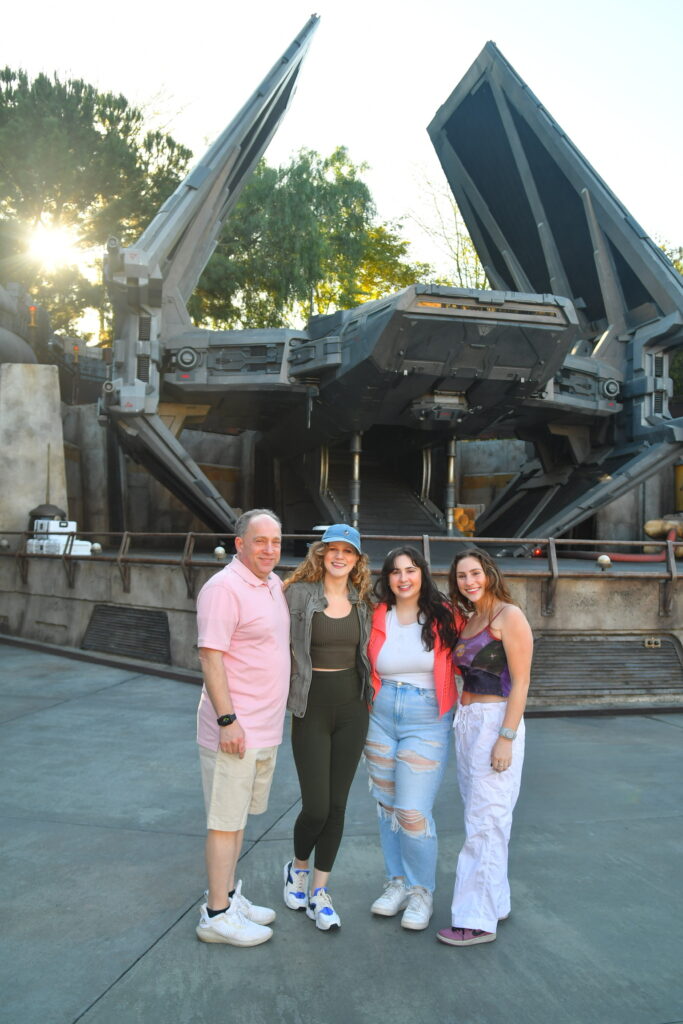 A group of four Disney Star Wars fans standing in front of the TIE Echelon ship at Star Wars: Galaxy's Edge.