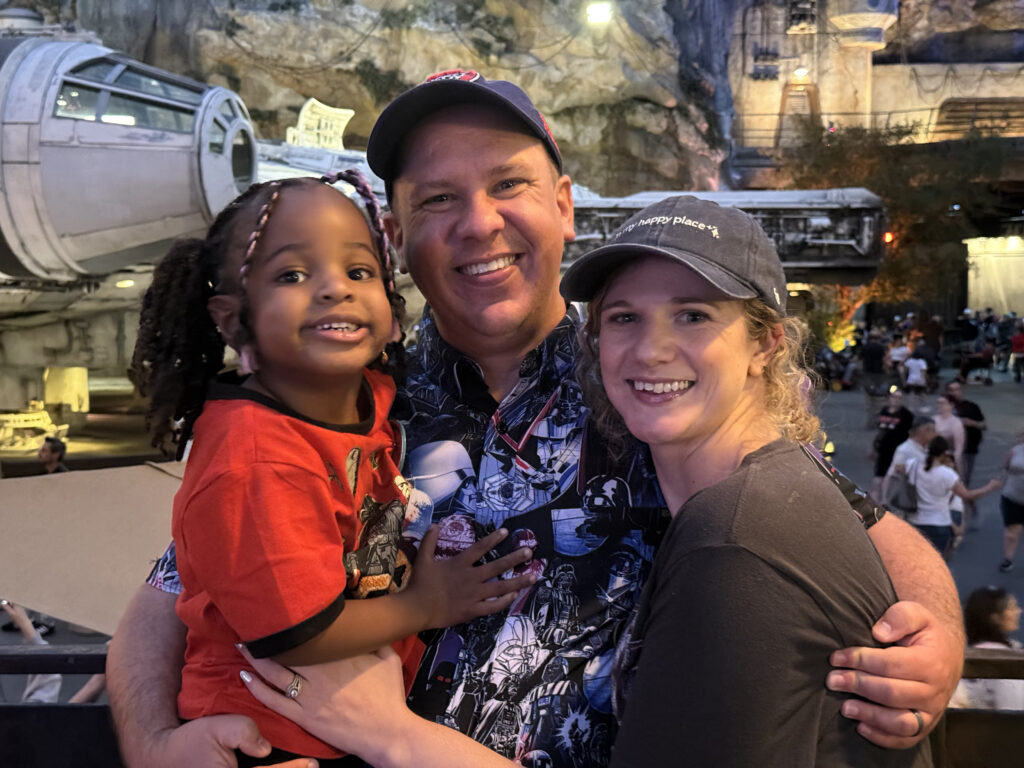 Family posing in themed Star Wars outfits in front of the Millennium Falcon