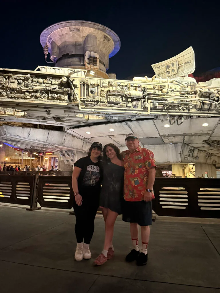 Family posing in themed Star Wars outfits in front of the Millennium Falcon