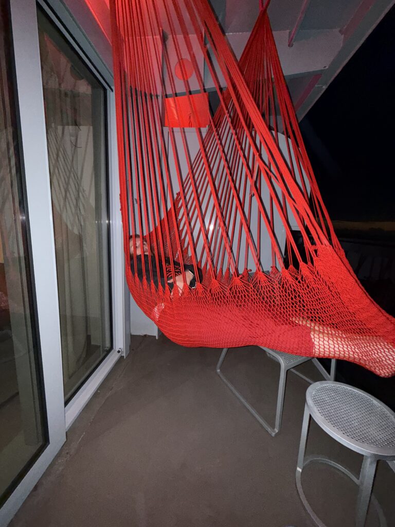 Relaxing in a Red Hammock at Night on the Virgin Voyages Scarlet Lady During a Sea Day